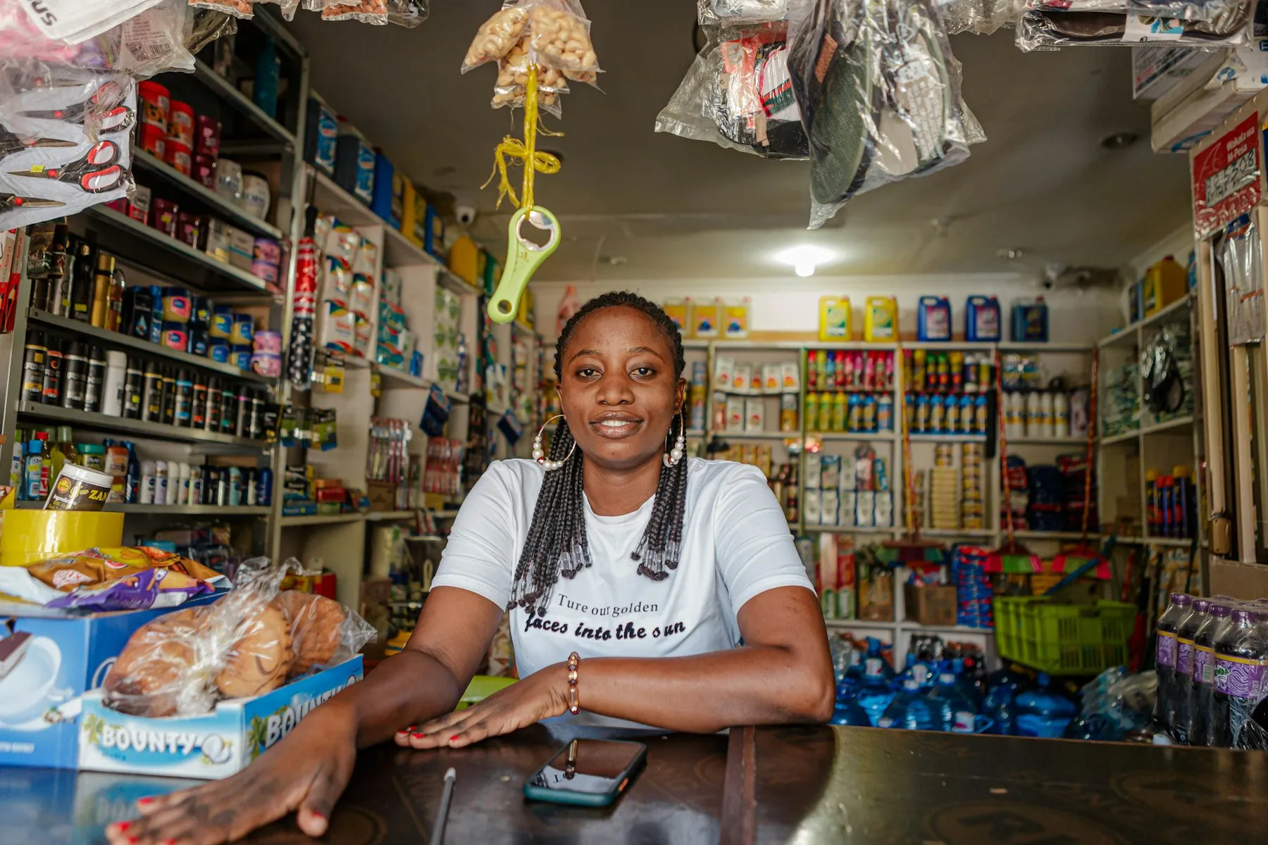 A smiling shopkeeper leaning on the counter of her well-stocked shop