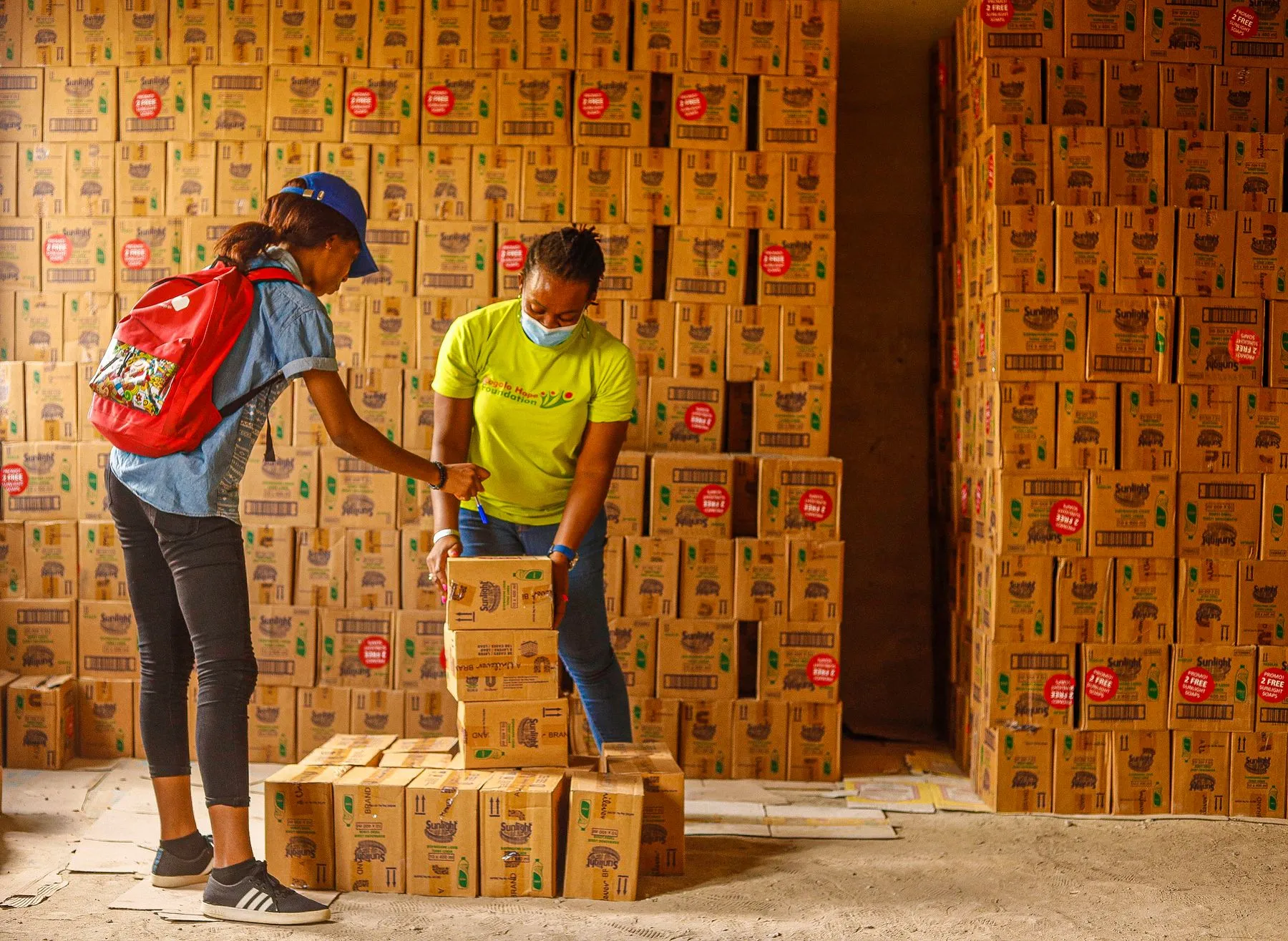 Two workers stacking cartons of stock in a warehouse